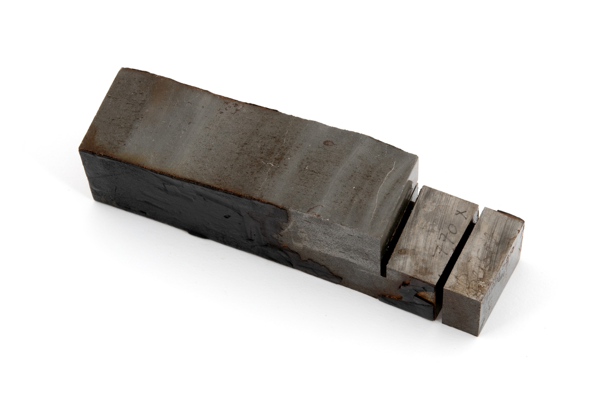 Metallprøve skåret ut fra bruddflate til stagdel fra D6 staget på riggen Alexander L. Kielland. 

Prøven viser regelmessige linjer "rastlinjer" i bruddflaten, og viser at sprekkens gradvise utvikling har medført at det har dannet seg et mønster i bruddflaten som kan sammenlignes med årringer i et tre. Slike linjer er typisk ved utmattingsbrudd og viser at metallet har gitt etter over tid. 

De to sidene av prøvestykket som tilsvarer stagveggens innside og utside er fremdeles delvis dekket med sort maling. 

Bokstaver og tall er stiplet inn i metallstykkets overflate. Det er sannsynlig at det ene av disse tallene henviser til avstand i centimeter fra initieringspunkt A for utmattingsbrudd. I dette metallstykket er tallet 770 risset inn som betyr at stykket sannsynligvis er skåret ut fra bruddflaten nærmere initeringspunkt B. 

I noen tilfeller omtales initieringspunktene A pg B som I og II.