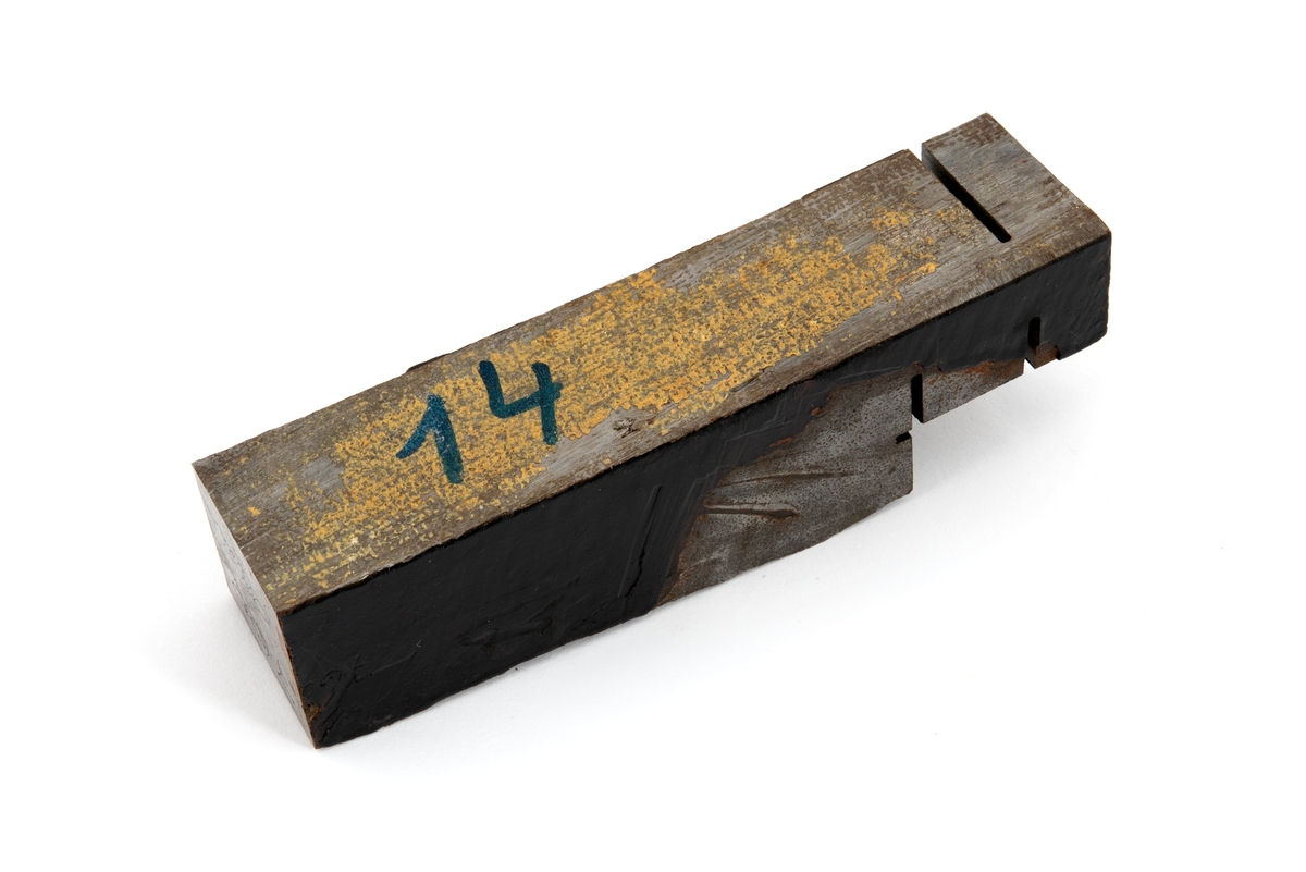 Metallprøve skåret ut fra bruddflate til stagdel fra D6 staget på riggen Alexander L. Kielland. 

Prøven viser regelmessige linjer "rastlinjer" i bruddflaten, og viser at sprekkens gradvise utvikling har medført at det har dannet seg et mønster i bruddflaten som kan sammenlignes med årringer i et tre. Slike linjer er typisk ved utmattingsbrudd og viser at metallet har gitt etter over tid. 

De to sidene av prøvestykket som tilsvarer stagveggens innside og utside er fremdeles delvis dekket med sort maling. 

Bokstaver og tall er stiplet inn i metallstykkets overflate. Det er sannsynlig at det ene av disse tallene henviser til avstand i centimeter fra initieringspunkt A for utmattingsbrudd. I dette metallstykket er tallet 770 risset inn som betyr at stykket sannsynligvis er skåret ut fra bruddflaten nærmere initeringspunkt B. 

I noen tilfeller omtales initieringspunktene A pg B som I og II.