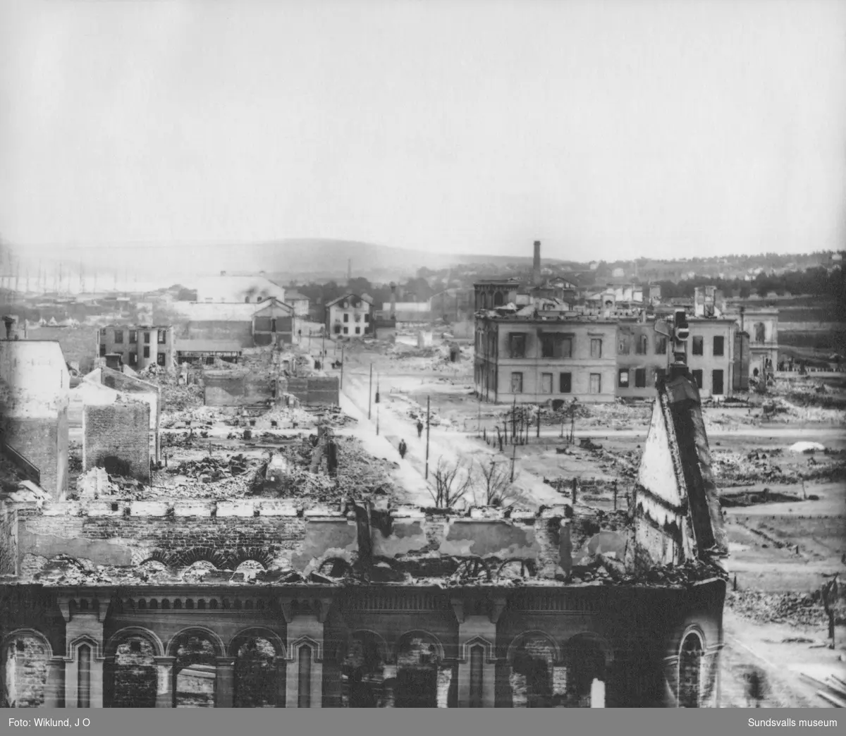 Sundsvalls stadsbrand 1888.  I förgrunden den brandskadade Betlehemskyrkan, senare Frimurarlogens hus. De byggnader som kvarstår är till vänster Stadshuset och Bankhuset och till höger Schack- och Läsesällskapets hus (W6).