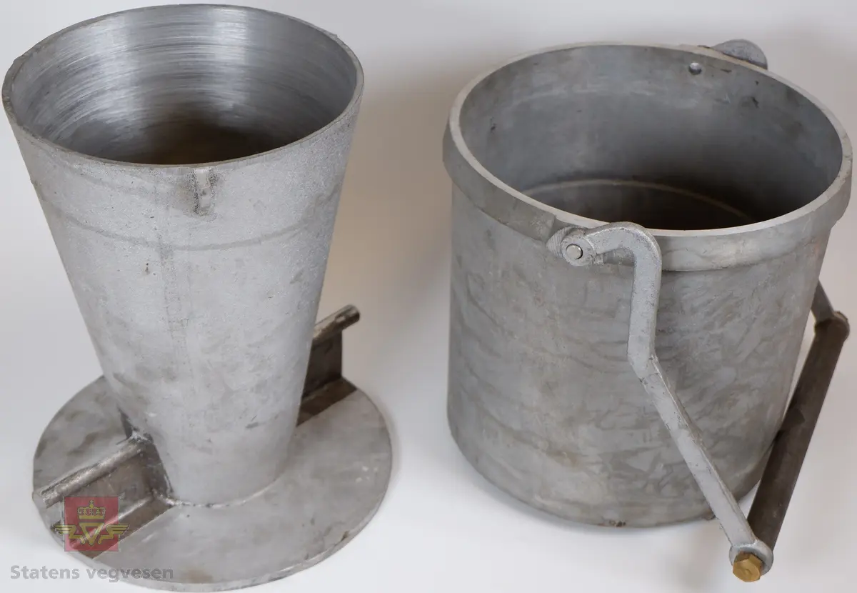 Ei trakt og et 10 liters målekar i aluminium. Ei glassplate samt bruksanvisninger i ei malt trekasse. Delene er kontrollmåler, trakt og 10 liters målekar. I lokket er det et rom for medfølgende glassplate.