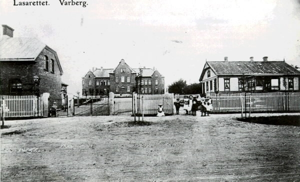 Vykort, " Lasarettet. Varberg". Länslasarettet invigdes 1901 i den södra delen av nuvarande kv Lasarettet. Den tidigare lasarettsbyggnaden från 1852 i kvarterets nordöstra del fortsatte att användas till köksavdelningen. Kvar stod också en byggnad, delvis av sten, med obduktionssal, bårhus, kurhus och sinnessjukhus. 1904 stod en ekonomibyggnad färdig, även inrymmande kontor, arkiv och personalbostäder. Då byggdes också en grindstuga i sten med bostad för portvakten och två rum för drängarna. Denna ses till vänster i bild och till höger i bild ses läkarvillan från 1883. De ligger utmed Prästgatan.