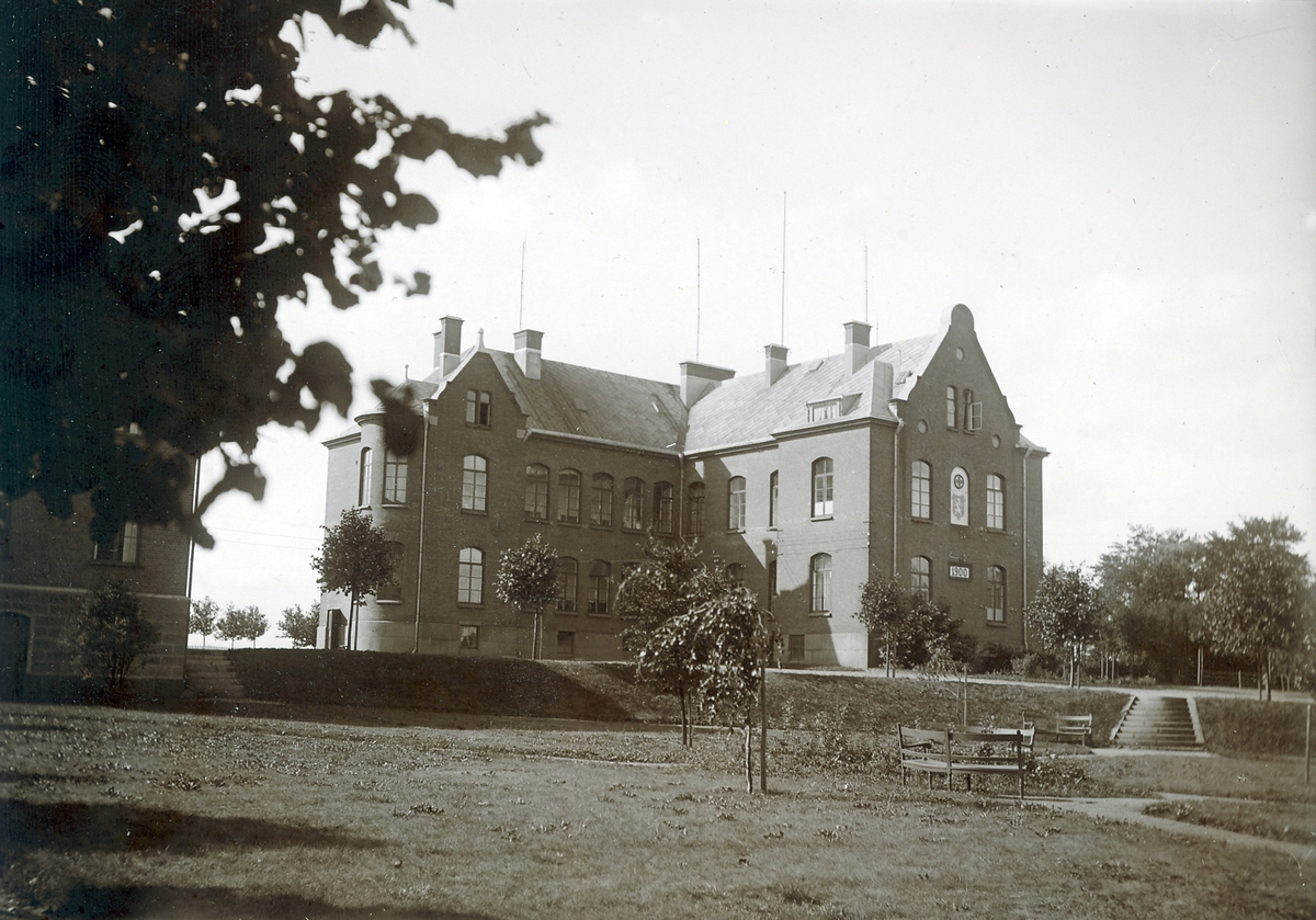 Ur byggmästare Johannes Nilssons fotoalbum från 1914. Varbergs lasarett, då benämnt Länslasarettet, invigdes den 30 november 1901. På husgaveln anges trots det årtalet 1900. Det efterträdde en sjukhusbyggnad av trä med 40 sängplatser, som uppförts 1852 på samma plats, då kallad Dykerilyckan. Dessförinnan hade länslasarettet varit förlagt till fästningen.

I förgrunden ses sjukhusparken med trädgårdsmöblemang i kvarterets nordöstra hörn där Västra Vallgatan och Prästgatan möts. Till vänster skymtar ekonomibyggnaden med personalbostäder, som uppfördes några år senare.