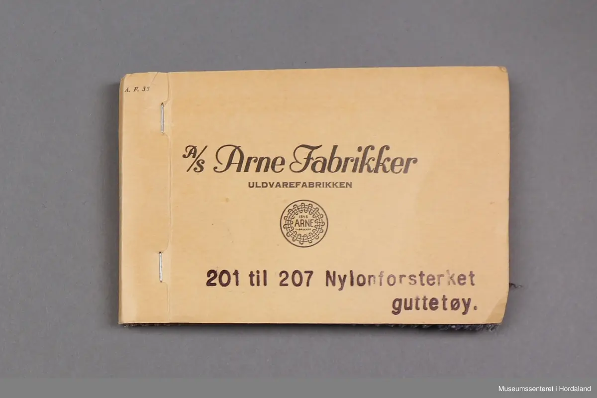 Mappe med rektangulære stoffprøver av vevd ullstoff frå ullvarefabrikken ved Arne Fabrikker. Desse er til nylonforsterka "guttetøy".