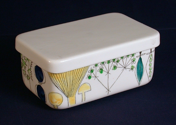 Rektangulär porslinsask med polykrom dekor med vitt, slätt lock. Asken har 2 st nedsänkningar snett mittemot varandra på askens långsidor.