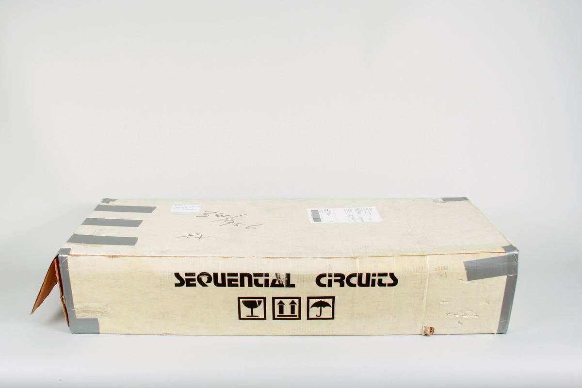 Kasse i tykk kartong til synthesizer. Original fra fabrikk.
Flere påførte adresser og merker etter transport.

Inne i kassen av kartong en blå fylling for stabilisering av instrumentet under transport.