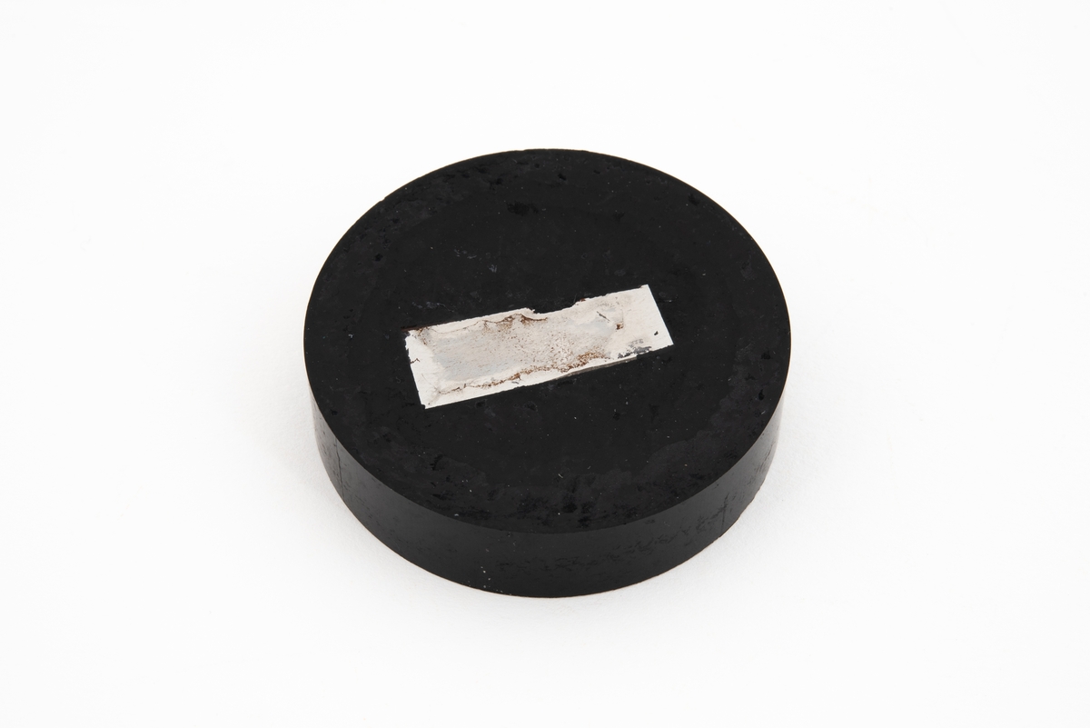 Metallprøve støpt inn i plastmateriale for undersøkelse i mikroskop. Overflaten ble polert for å gjøre det mulig å kunne se strukturen i metallet.

Det er sannsynlig at prøven kommer fra utrivningsbruddene i området rundt kilsveisen som festet hydrofonholderen til stag D6. Det var her utmattingsbruddene i staget startet.