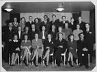 Gruppbild med ett stort antal kvinnor och män, sittande och stående i tre rader. Medlemmar i 
