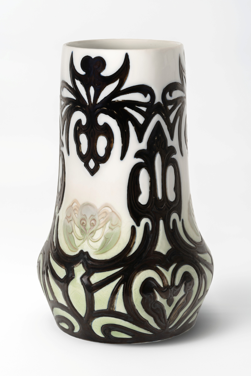 Monumental balusterformet vase i glasert porselen. Nedre del av korpus er dekorert med en grønntonet underglasurmaling. På vasens forside er det en stilisert fremstilling av en kreps. Resten av korpus er dekket med et kraftige sortfargede ornamenter i relieff.