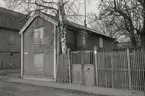 Ett bostadshus med lockläcktpanel och igenbommade fönster. Staket till höger bredvid huset på Strandgatan.
