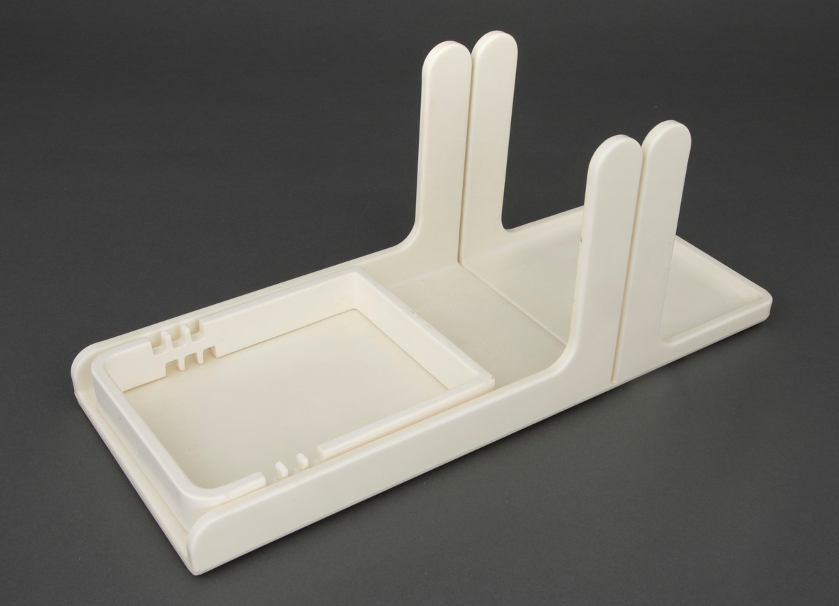 Skjærebrett som består av et støttebrett og en løs innsettingsramme, alt i hvit propenplast. Brettet har lave støttekanter og tvers over er det en slisse der knivene føres ved skjæring. Den løse rammen har seks par utsparinger som passer i brettets endekant og regulerer avstanden til skjæreslissen. På brettets underside er det seks små, grå plastklosser som hindrer brettet å gli.