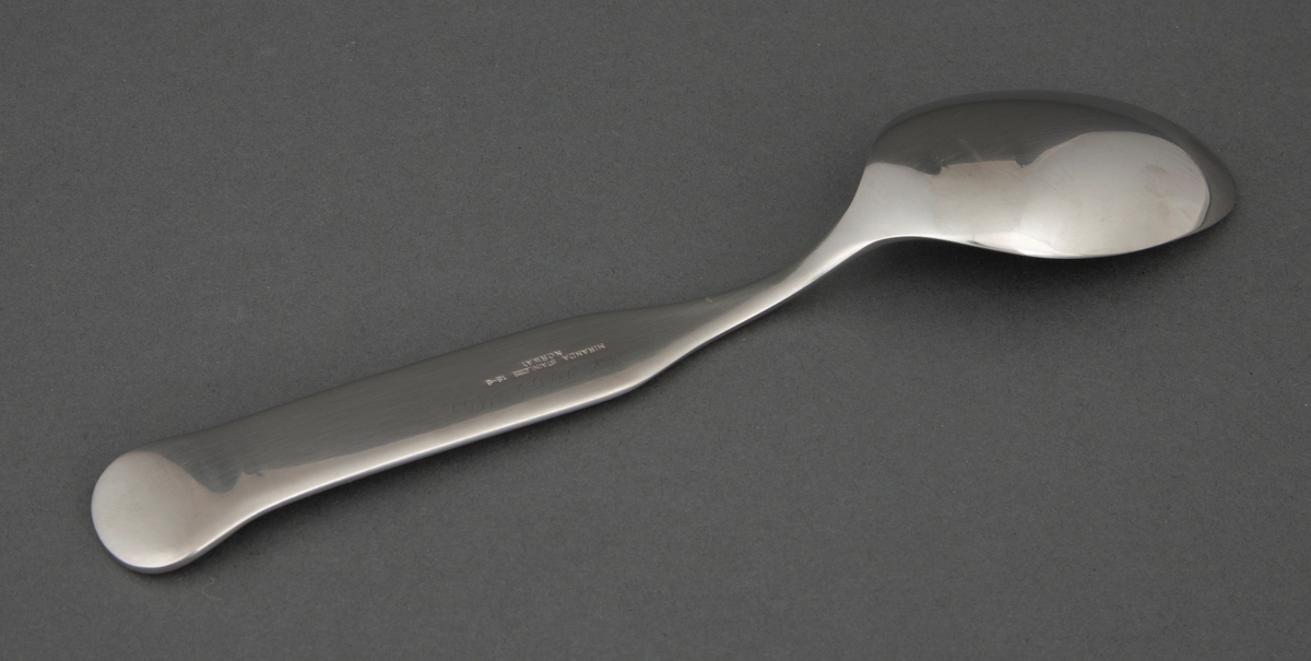 Spiseskje i presset, rustfritt stål med ovalt skjeblad. Skaftet er smalt ved roten og tiltar i bredde og er rett