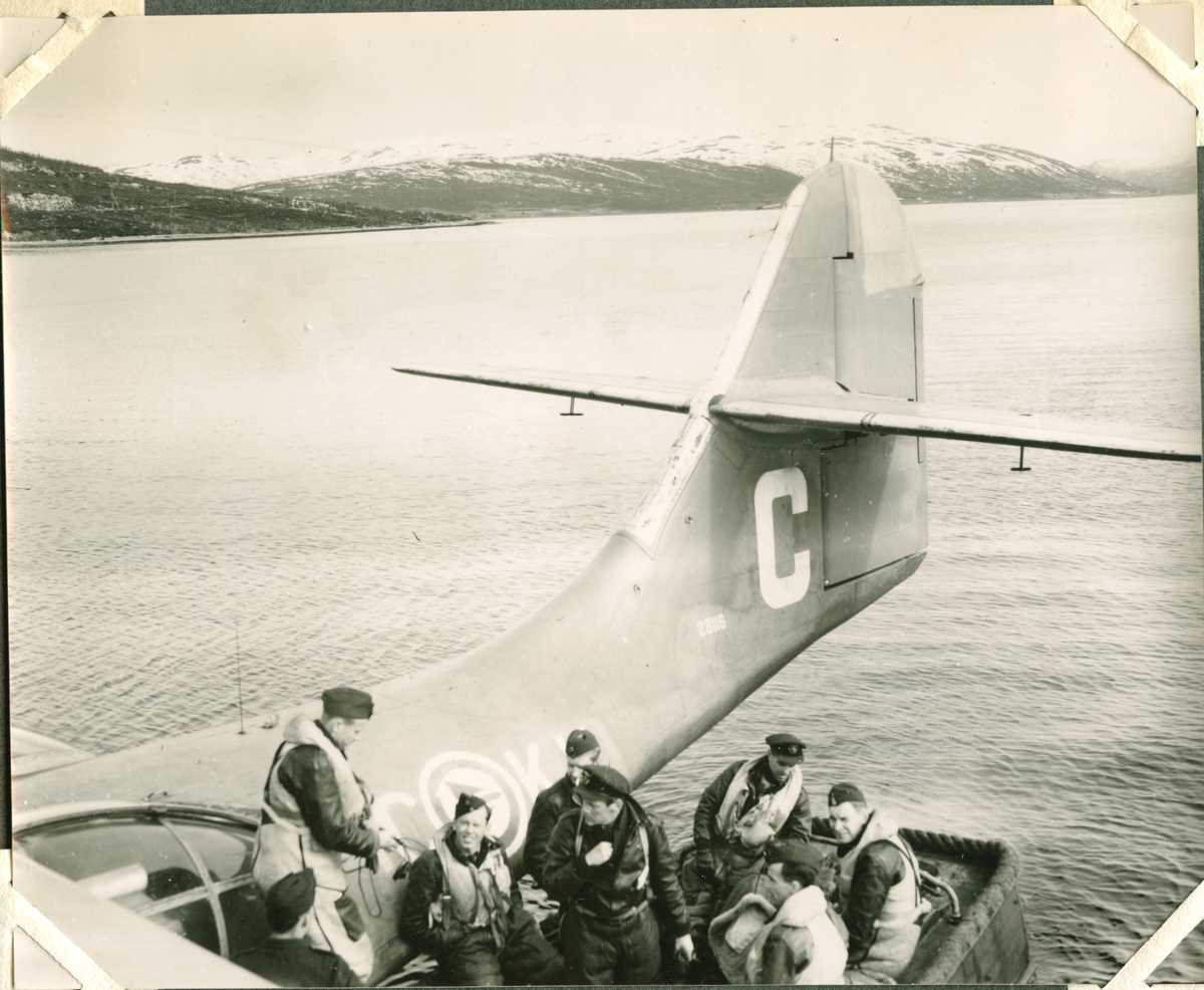 Catalina som har vært på Svalbard. Her er de på flystasjonen på Skattøra. Navigatøren Jan A. Søstrand  forteller:  Første gangen jeg var på Svalbard var 26. mai 1952 med KKC. kaptein Solem som skipper. Har noen fine bilder av hele mannskapet idet vi stiger opp i båten på Skattøra. Var heldigvis ikke med i 54. Da var jeg på Krigsskolen, men jeg hadde 3 turer til, pluss en tur til Jan Mayen sommeren 54 (ingen flyplass der den gang). Jeg var navigatør. Det var 2 flygere, vanligvis bare 1 navigatør, 1 maskinist, 2 telegrafister. På lengre turer kunne vi være flere. Jeg kan ikke huske datoene på de andre turene. Den ene turen til Ny Ålesund var i forbindelse med gruveulykken der. Vi hadde med medisinsk utstyr som ble droppet på samme måte som med posten. Jeg tok bildet. Jan Mayen- turen var i regi av Polarinstituttet og var et rent fotooppdrag. Vi hadde med en professor, tror jeg han var, som hadde ansvar for fotograferingen, men bildene av vulkanen tok jeg med stort flykamera.