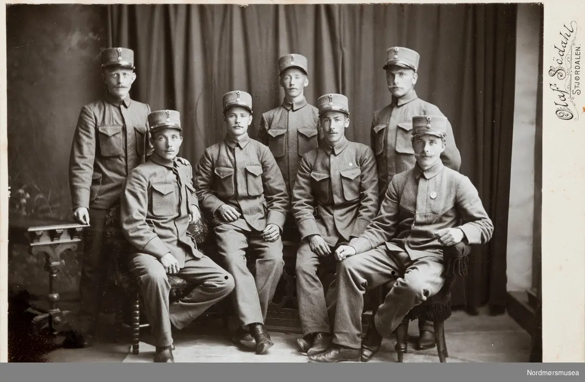 Gruppe soldater. Ukjent hvem vi ser på bildet. Kabinett-fotografi. Familiealbum trolig etter familien Vahlen, bosatt på Dahle, nå under Kristiansund kommune. Hovedsaklig type Carte de visite. Funnet ved rydding av dødsbo. Donert til museet 17.09.2021.