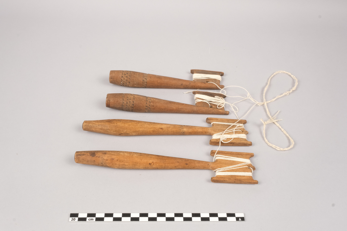 Ett sett slingrestrokker, 4 styker av to varianter, alle er av tre. To av stokkene er med dekorert håndtak og enkeltside hode for anleggelse av tråd. Hullet er plassert inn mot stokken omtrent midt på hodets lengde. Håndtaket er har et tilnærmet ovalt tverrsnitt som smalner ut mot hodet og mot den butte nedre enden. Håndtaket er dekorert med omgivende geometrisk dekor utgjort av trekanter som er skåret ut av treverket, samt tre linjer nederst på håndtaket. De to siste stokkene er med dobbelt hode for anleggelse av tråd på begge sider av stokken. Hullet er plassert mot enden, midt mellom utsvingingen av hodene. Håndtakene er uten dekor og har et tilnærmet ovalt tverrsnitt som smalner ut mot hodet og mot den butte nedre enden. De fire stokkene henger sammen via et påbegynt slingring stykke med bomullstråd.