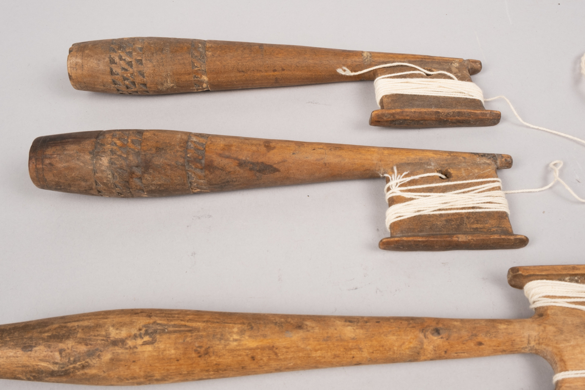Ett sett slingrestrokker, 4 styker av to varianter, alle er av tre. To av stokkene er med dekorert håndtak og enkeltside hode for anleggelse av tråd. Hullet er plassert inn mot stokken omtrent midt på hodets lengde. Håndtaket er har et tilnærmet ovalt tverrsnitt som smalner ut mot hodet og mot den butte nedre enden. Håndtaket er dekorert med omgivende geometrisk dekor utgjort av trekanter som er skåret ut av treverket, samt tre linjer nederst på håndtaket. De to siste stokkene er med dobbelt hode for anleggelse av tråd på begge sider av stokken. Hullet er plassert mot enden, midt mellom utsvingingen av hodene. Håndtakene er uten dekor og har et tilnærmet ovalt tverrsnitt som smalner ut mot hodet og mot den butte nedre enden. De fire stokkene henger sammen via et påbegynt slingring stykke med bomullstråd.