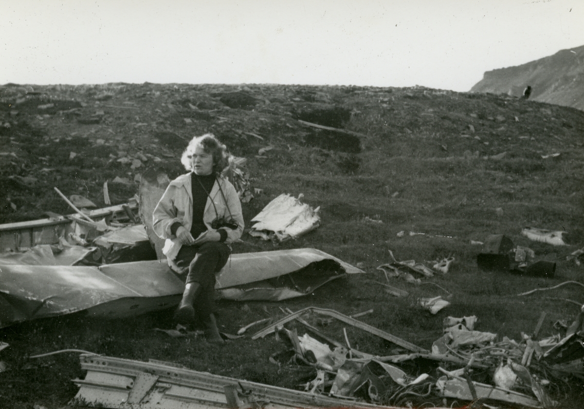 Dame som sitter på et flyvrak i Hiorthhamn. Flyet var en tysk Junker som ble beskutt av den norske garnisonen i Longyearbyen og deretter styrtet etter å ha fløyet inn i taubanekabler i Hiorthhamn 23.juli 1942. De fire tyskerne som var om bord ble begravet av nordmennene i Hiorthhamn. I 1958 ble de sendt til Norge og begravet på krigskirkegården på Botn på Rognan. De fire døde var Erich W. Etienne, Vollrath Wiebel, Heinz Wagner og Heinrich Voss.