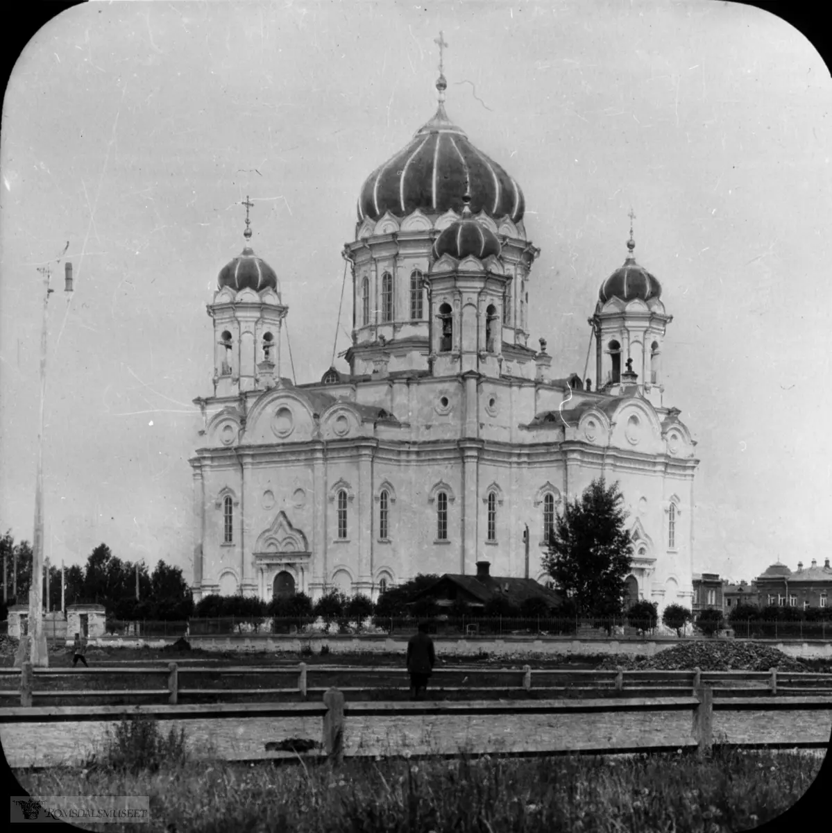 Fra Jonas Lied samlingen., "Trinity Cathedral" i Tomsk, Russland. Katedralen var den viktigste ortodokse kirken i Tomsk bispedømme i perioden 1900-1930. Den lå på Novosobornaya-plassen i Tomsk. Bygningen ble påbegynt i 1844, men takkuppelen kollapset i 1850 og drepte fire mennesker. Arbeidet ble gjenopptatt i 1858, men ble snart suspendert på grunn av kostnadsoverskridelser og et kjølig klima "for den hellige sak". Det var først i 1885-1889 at kirken ble fullført av byarkitekt V.V. Khabarov. Utsmykningen av katedralen fortsatte til sommeren 1900. I 1930 ble katedralen stengt og i 1934 ble den revet og det istedet anlagt et torg på plassen der kirken stod.