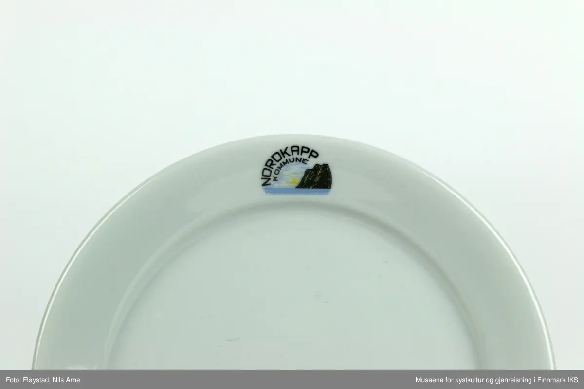 Et lite og rundt kaffefat, eller serveringsfat med opphøyd kant.  Fatet er laget av feltspatporselen med hvit glasur og trykt dekor øverst på kanten. 

Dekoren består av et sirkulært bunttrykk med motiv av Nordkapplatået i solskinn og en lettskyet himmel. Ved siden av platået er "NORDKAPP KOMMUNE" trykt i en buet form.