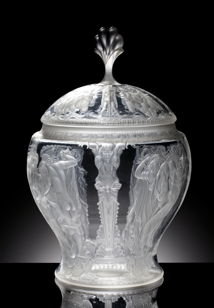 Formgiven av Simon Gate, gravyrarbete utfört av Gustav Abels. "Oxhuvudena", stor urna (eller pokal) med lock. Gravyr med motiv består av fyra scener, samtliga innehållande kvinnor i olika scener, och i en scen finns även ett barn. Dessa motiv ramas in av fyra graverade pelare, vilka uppåt avslutas med en mytologisk gestalt. Locket graverat motiv bestående av tjurhuvuden i fyra grupper om två eller tre stycken huvuden. Mellan dessa människogestalter med svärd som sticks ner i marken. Överst en knopp i form av en plym.