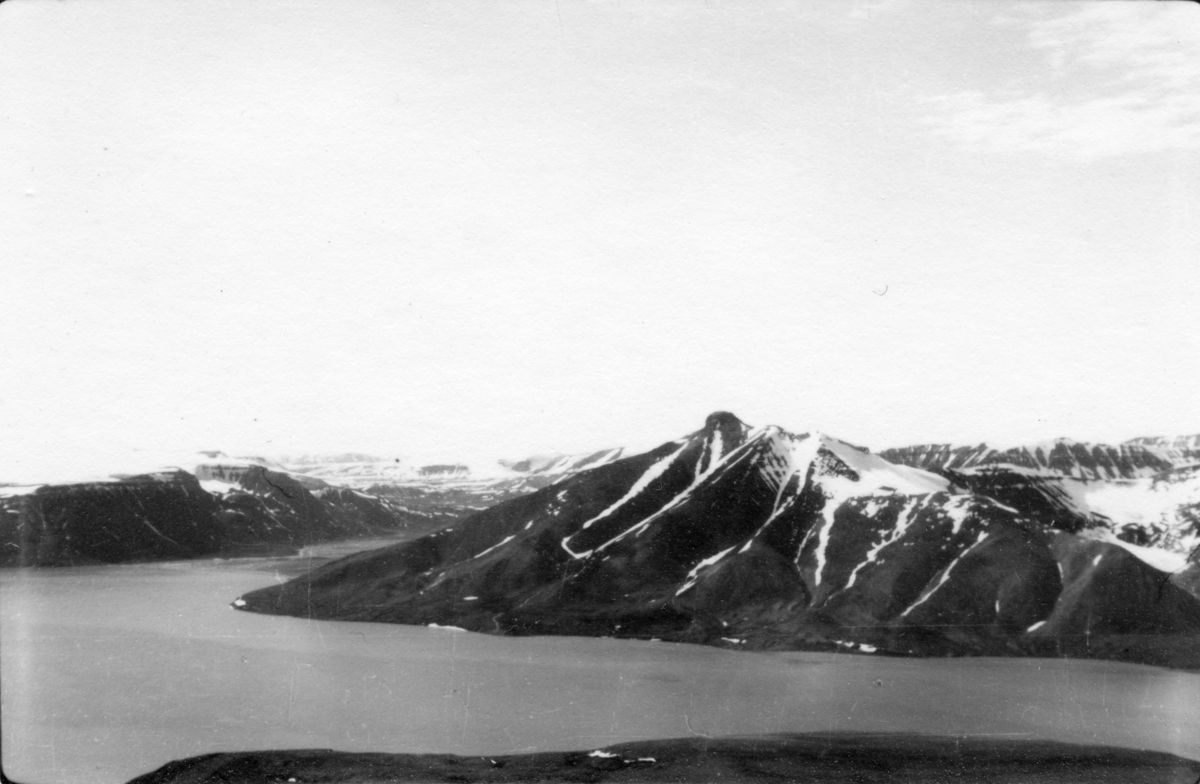 Utsikt mot Pyramiden fra Wordiekammen. Bildet kommer fra The Cambridge Spitsbergen Expedition. Ekspedisjonen besto av seks menn, de fleste var geomorfologer, som dro fra England til Svalbard via Nordkapp og Bjørnøya om bord på Lyngen sommeren 1938. Målet deres var å kartlegge området rundt Nordenskioldbreen, Gipsvika og Brucebyen.