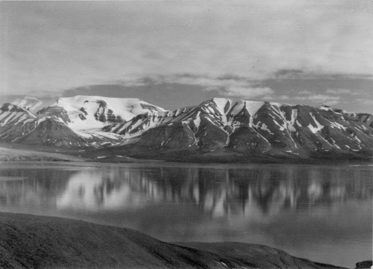 Robertfjellet og Carrondalen sett fra Adolfbukta.  Bildet kommer fra The Cambridge Spitsbergen Expedition. Ekspedisjonen besto av seks menn, de fleste var geomorfologer, som dro fra England til Svalbard via Nordkapp og Bjørnøya om bord på Lyngen sommeren 1938. Målet deres var å kartlegge området rundt Nordenskioldbreen, Gipsvika og Brucebyen.