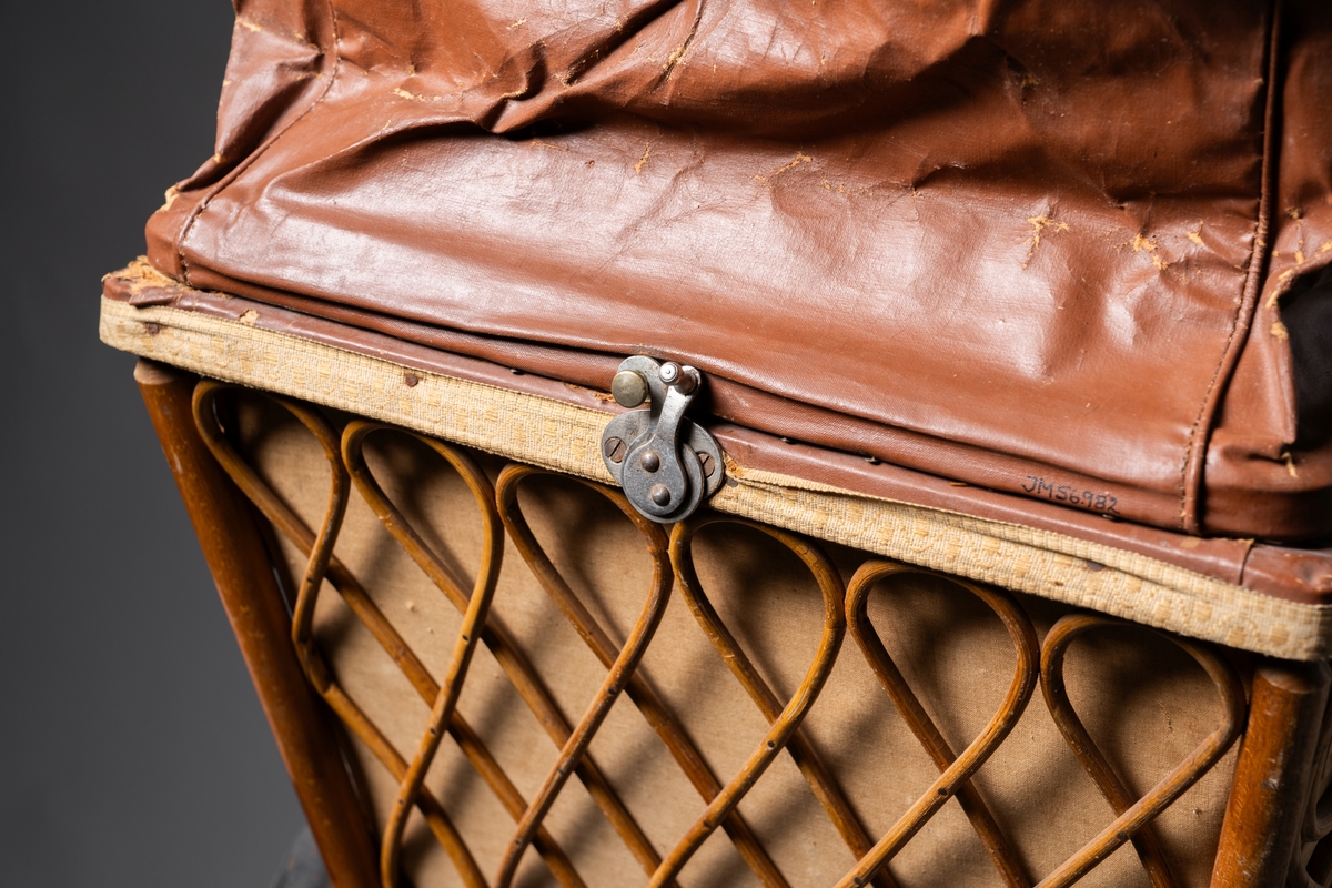 Barnvagn, kombinerad ligg- och sittvagn. Fotlådan går att fälla upp/ner till liggande respektive sittande läge. Stomme av järn bestående av underrede med två stora framhjul och två små bakhjul, samt två stödben (så att vagnen inte tippar fram). Hjulen är av trä med plåtskoning och ekrar av järn. Korg av trä, betsat, dekorerad utvändigt med böjd rotting. Invändigt fodrad med brunt konstläder. Stoppad sits. Två höga, böjda trähandtag. Sufflett av brunt konstläder på metallställning. Suffletten går att fälla upp och ner samt går att ta av. Handtag av vitt porslin. Runt sufflettens ytterkant är ett textilt band med udd fäst. Bandet har ursprungligen varit fäst med nubb, senare fäst med häftstift (de två översta på höger sida i samband med registreringen). Band av textil runt kanten under suffletten.  Sits och fotlådan nötta, skador på suffletten.