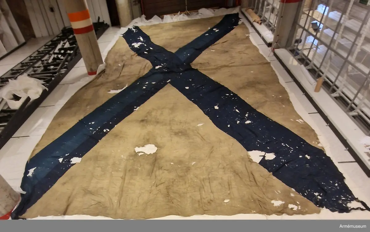 Flagga av fin flaggduk, vit med ett blått S:t Andreaskors. Vid stångsidan en förstärkning med snören som ska fästa flaggan i riggen. Även själva flaggan är förstärkt med extra lager blått tyg närmast stångsidan. "T 94" broderat på det vita fältet.