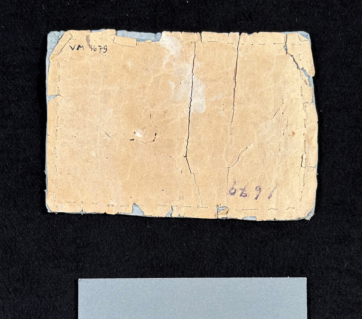 Märkduk av tuskaftat linne, sydd med korssöm. Alfabetet i mitten , bård runt om i rosa och ljusblått. Kantad med ljusblått tuskaftad bomull. Uppfodrad och fastsydd på papper.