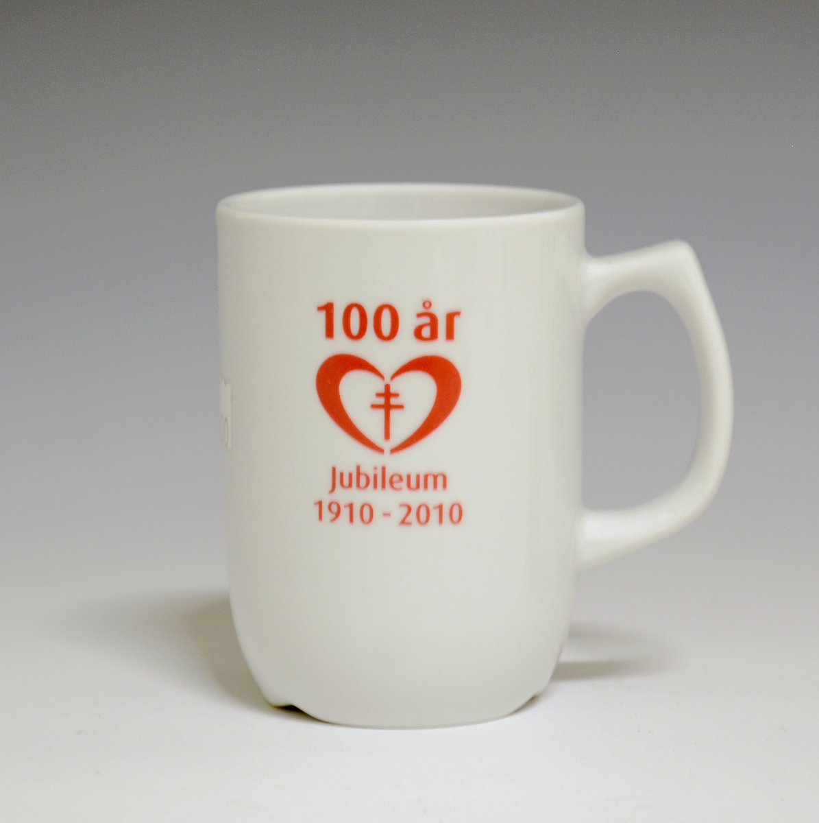 Krus av porselen med  hvit glasur. Påskriften "Nasjonalforeningen for folkehelsen 100 år 1910-2010" i rødt på begge sider av kruset.
Modell: Form av Tias Eckhoff
