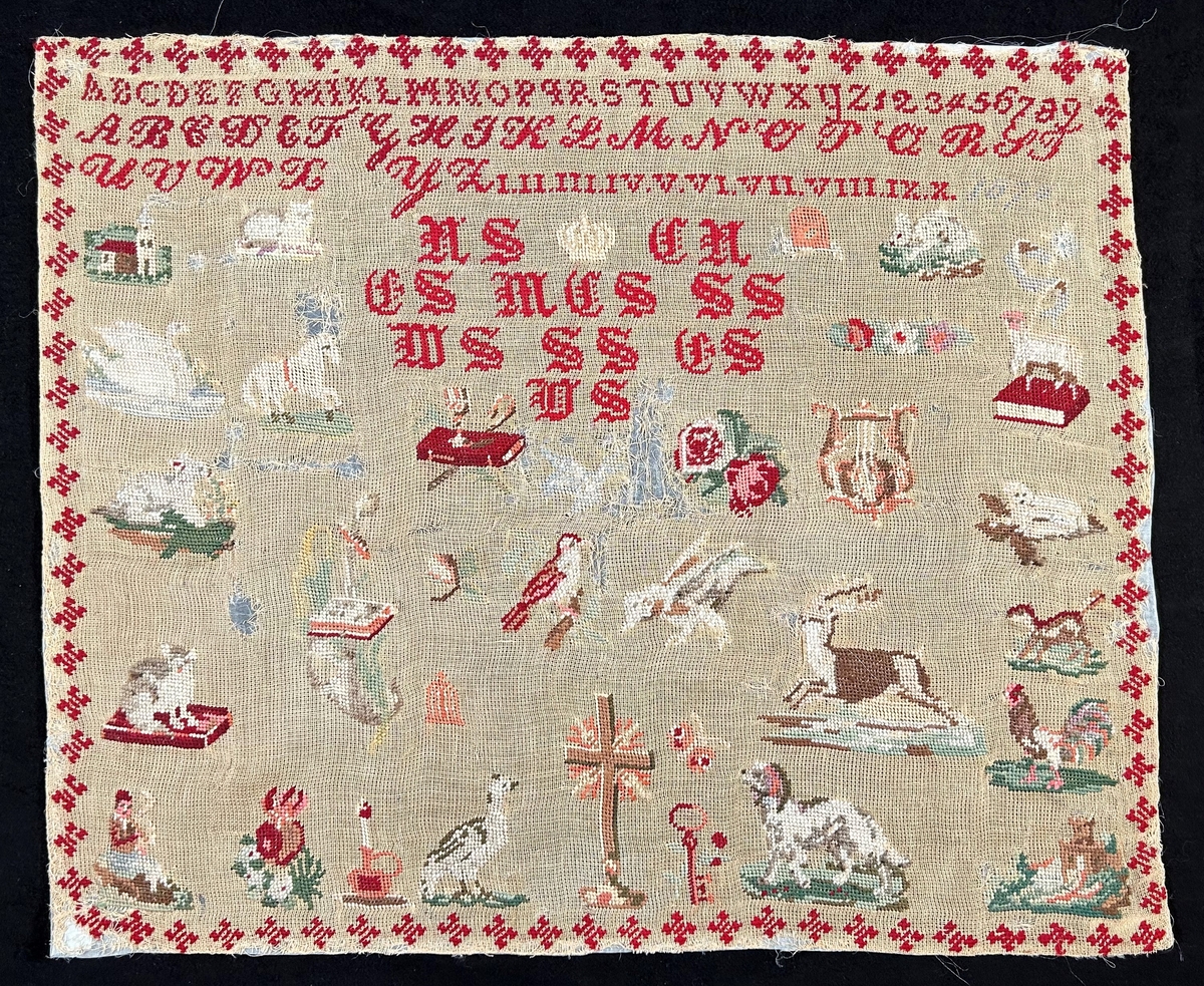 Märkduk med broderi på beige stramalj. Färger i rött, grönt, brunt och vitt. Tre bårder upptill med alfabetet i olika stilar, siffror (även romerska). Under en vit broderad krona, monogram i frakturstil. Strödda motiv över hela duken: blommor, djur, böcker, lyra, nyckel, ljus, med flera symboler. Längst ned i mitten ett kors.