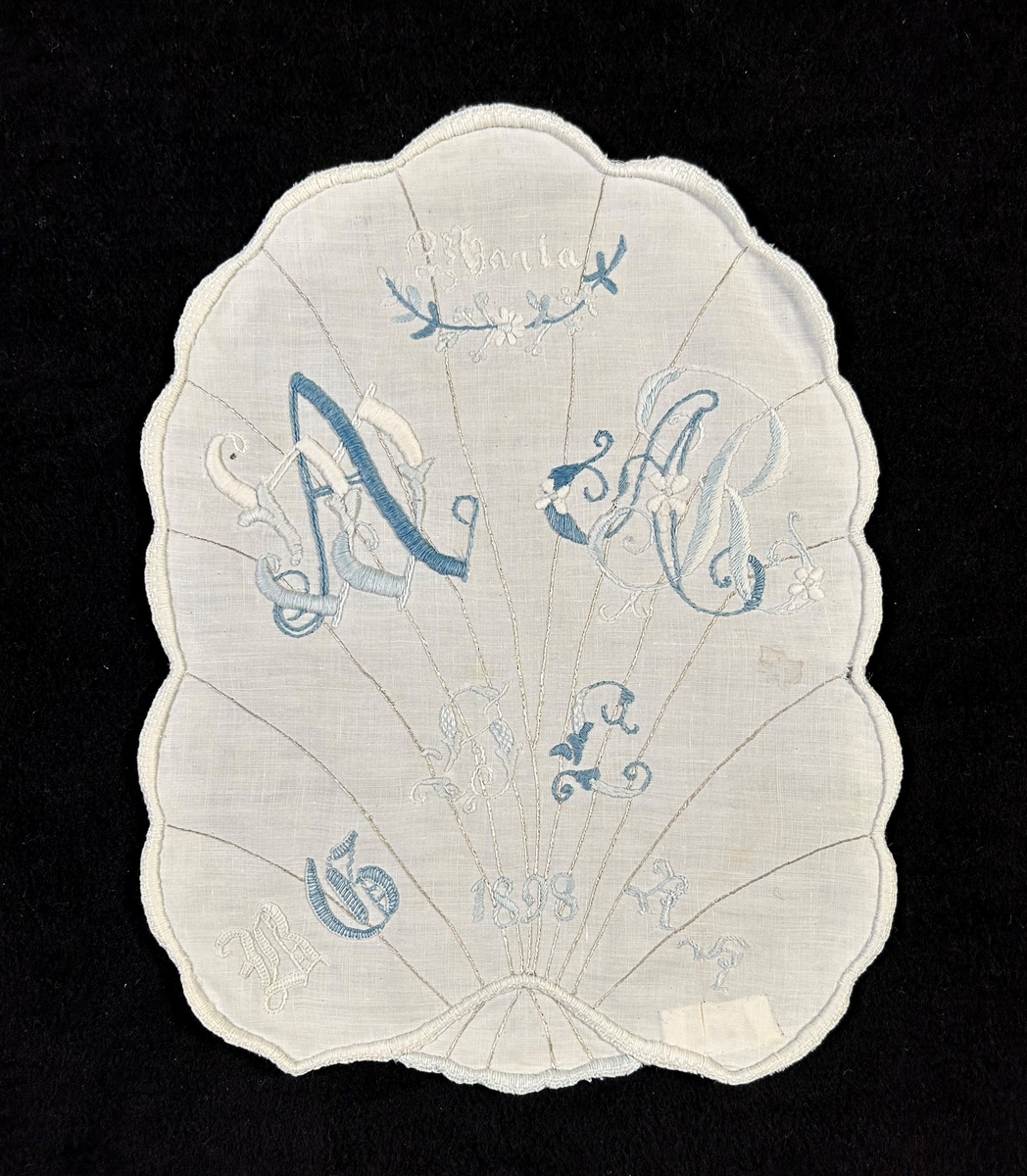 Märkduk av vitt linne med formen av ett blad med nerver av beige silke i stjälksöm. Allt märkt i blått och vitt märkgarn. Vit langett runt om.