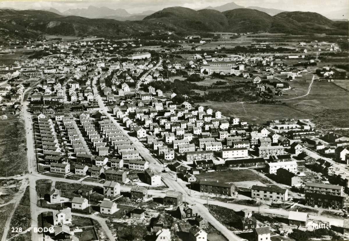 Flyfoto av de vestlige boligområdene i Bodø. Sentralt og til venstre i bildet ses "Svenskbyen". Dette var prefabrikerte hus gitt som nødhjelp av svenske Røde Kors, til erstatning for de husene som gikk tapt under den tyske bombingen i mai 1940. Husene ble reist under krigen. Øvrig bebyggelse ble reist tidlig på 1950-tallet. Lengre bak ses den nye Bankgata skole.