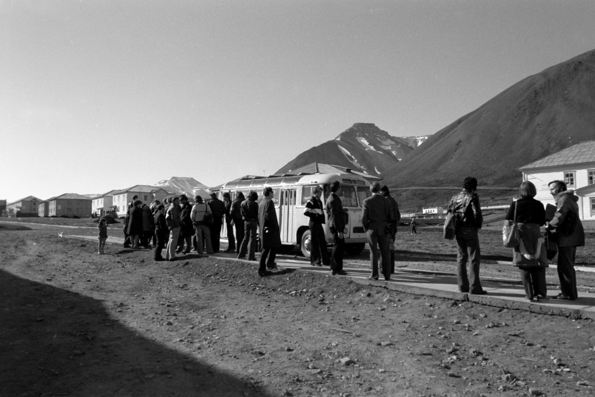 Folk ved buss på hovedgata i Pyramiden.