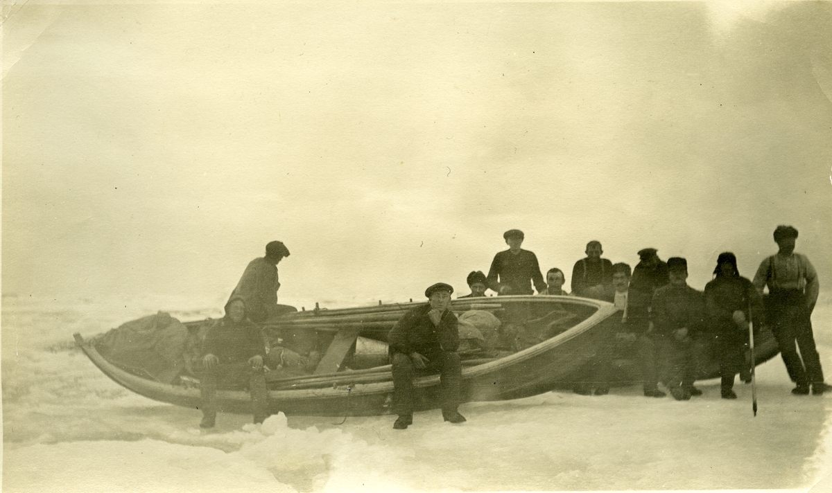 12 menn med en båt setter i land utstyr, tønner og mat et ukjent sted på Svalbard. Jens Kristoffer Bay var vinteren 1914/15 sjef for en overvintringsekspedisjon på Svalbard, og det er mulig at bildet er fra denne ekspedisjonen. Bilde fra Jens K. Bay sin bildesamling.