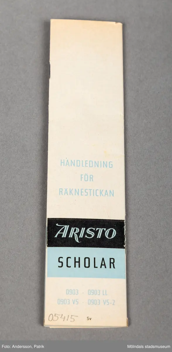 En avlång blå pappask som innehåller en räknesticka. Asken är tvådelad och kan dras isär i sidled. På varje del av en askens del av framsida finns en liten bild av en stjärna. På högra  delen finns en bild av två små halva solar. Under solar finns en text med namnet på räknestickans modell. Vid öppnandet av ask kan man med handskrivna bokstäver se namnet Karin Petterson.
Inuti asken finns en vit räknsticka i trä med en skjutbar mätdel i plast och metall.
Det finns också en medföljande separat användningsbeskrivning.