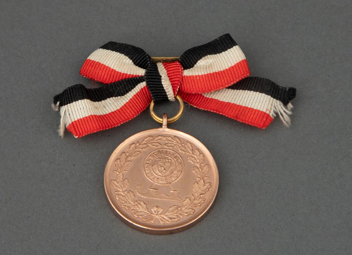 Rund medalje i bronse med opphøyet rand og punslet dekor. På avers er det en laurbærkrans, en hornskøyte og et rundt felt med Berlins våpen. På revers er det en laurbærkrans og gravert tekst. Medaljen er festet til en nål med sløyfe i ripsbånd med hvite, røde og svarte striper.