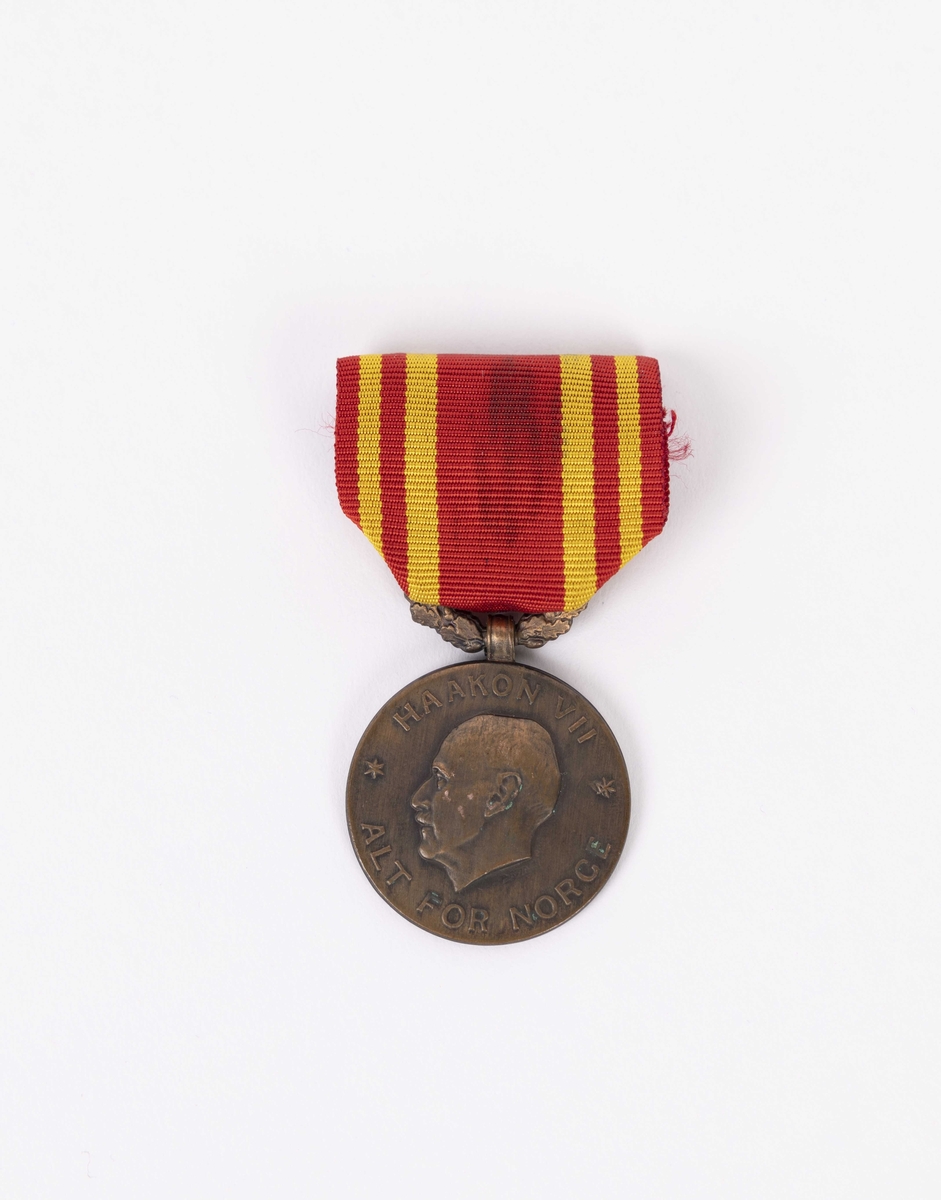 Medalje: Profilprotrett av Kong Haakon VII på forside og tekst og dekor på baksiden.