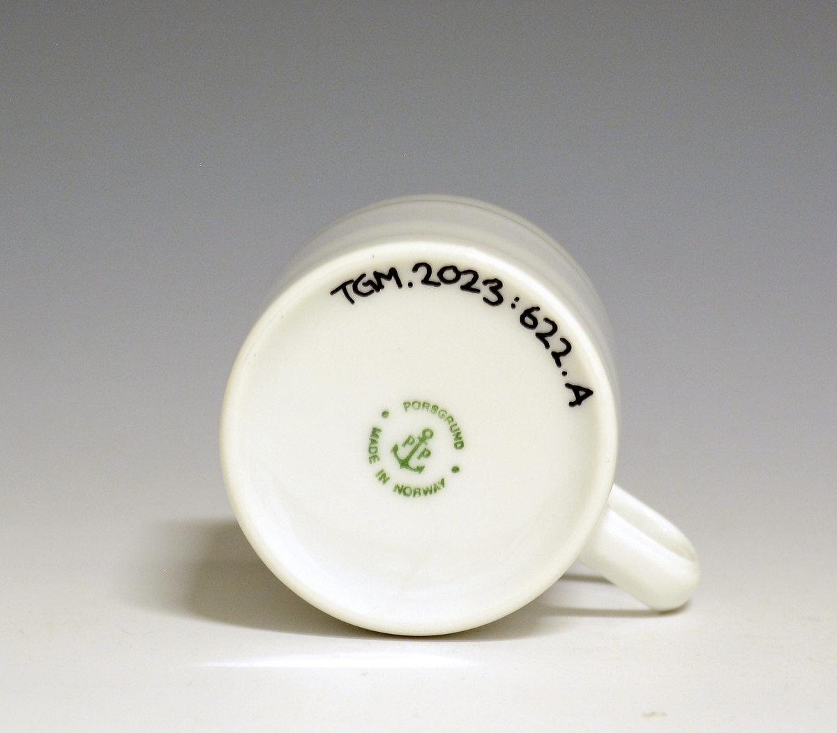 Kopp av porselen med hvit glasur. Dekorert med to enkle striper i platina med et grått bånd i mellom øverst på korpus.
Modell: Saturn
Dekor: Platina
