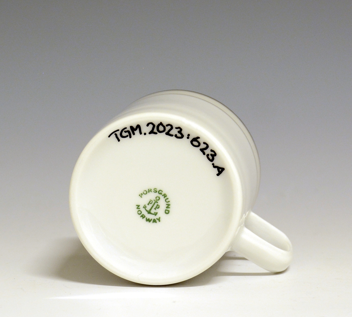 Kopp av porselen med hvit glasur. Dekorert med to enkle striper i platina med et grått bånd i mellom øverst på korpus.
Modell: Saturn
Dekor: Platina
