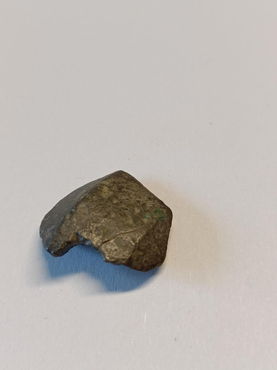 Fragment av sverdknapp/ hjalt. delen som er bevart er buet og viser trolig ytterkant og de fasede sidene av en sverdknapp. Fragmentet har også merker av et hulrom på innsiden, til festet.