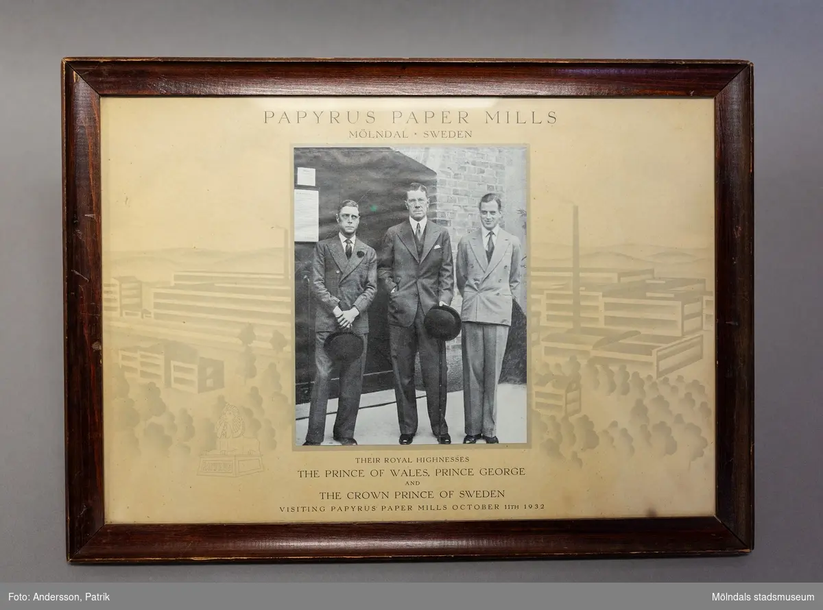 Ett inramat fotografi som föreställer prinsen av Wales, Prins George och dåvarande kronprins Gustav VI Adolf vid ett besök på Papayrusfabriken i Mölndal år 1932. Fotografiet har en beige passepartout med en svagt tonad grå/beige bakgrund föreställande en siluett av området vid papyrusfabriken.
Under fotot finns texten: Their Royal Highnesses The Prince of Wales, Prince George and The Crown Prince of Sweden visiting Papyrus Paper Mills
October 11TH 1932. Längst upp på tavlan står det Papyrus Paper Mills
Mölndal Sweden.
Bilden har en brun medeltjock konkavt formad träram.
På baksidan av tavlan finns ett emblem som anger: Aktiebolaget Ferm & Persson förgyllerietablissement.