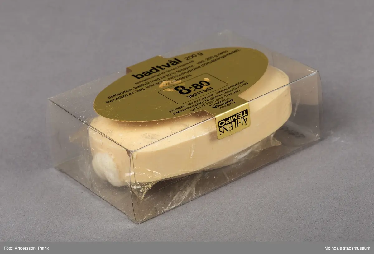 En genomskinlig plastförpackning som innehåller en upphängningsbar badtvål. Badtvålen är vaniljgul och har ett vitt snurrat rep för upphängning fäst i tvålens ände.
På askens framsida finns en guldfärgad oval dekal. På dekalen finns en innehållsdeklaration.
Det finns också en stor inramad ruta med angivet pris. På askens sida finns företagsnamnet Åhlens Tempo angivet.
Tvålen är tillverkad av företaget Victoria som började tillverka tvålar redan 1914.