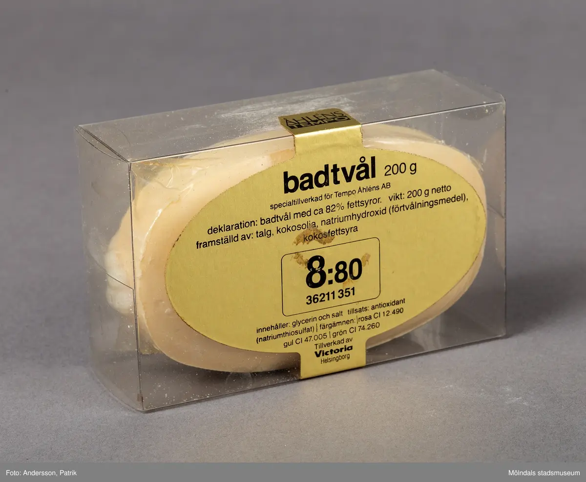En genomskinlig plastförpackning som innehåller en upphängningsbar badtvål. Badtvålen är vaniljgul och har ett vitt snurrat rep för upphängning fäst i tvålens ände.
På askens framsida finns en guldfärgad oval dekal. På dekalen finns en innehållsdeklaration.
Det finns också en stor inramad ruta med angivet pris. På askens sida finns företagsnamnet Åhlens Tempo angivet.
Tvålen är tillverkad av företaget Victoria som började tillverka tvålar redan 1914.