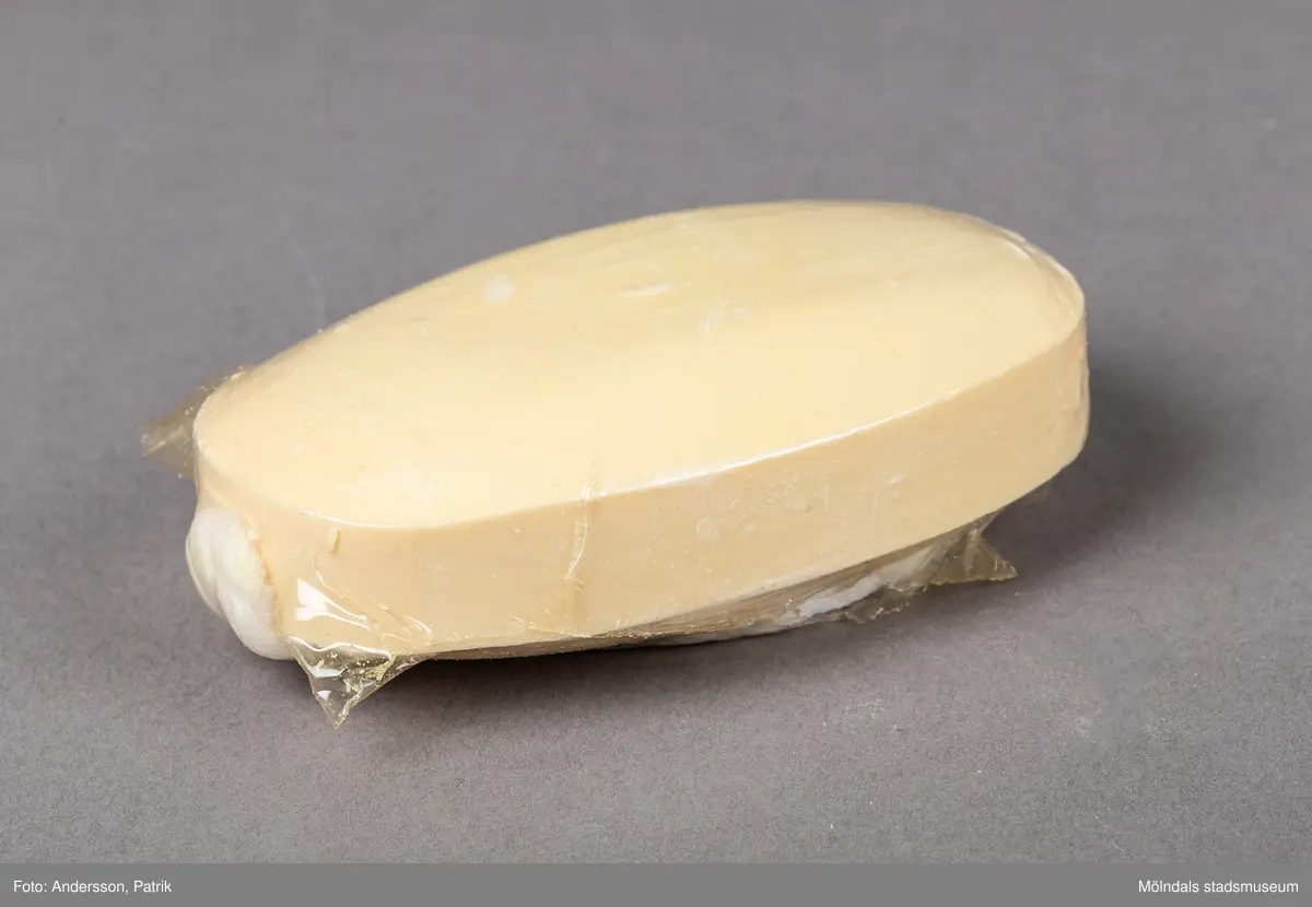 En genomskinlig plastförpackning som innehåller en upphängningsbar badtvål. Badtvålen är vaniljgul och har ett vitt snurrat rep för upphängning fäst i tvålens ände.
På askens framsida finns en guldfärgad oval dekal. På dekalen finns en innehållsdeklaration.
Det finns också en stor inramad ruta med angivet pris. På askens sida finns företagsnamnet Åhlens Tempo angivet.
Tvålen är tillverkad av företaget Victoria som började tillverka tvålar redan 1914.