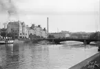 I olika tempon tar man sig över Saltängsbron i Norrköping en sommardag året 1899. Vid tiden kallade man överfarten Oscar Fredriks bro, uppkallad efter arvfursten, hertigen av Östergötland och sedermera kung Oscar II. Vy från Norra Strömsgatan.