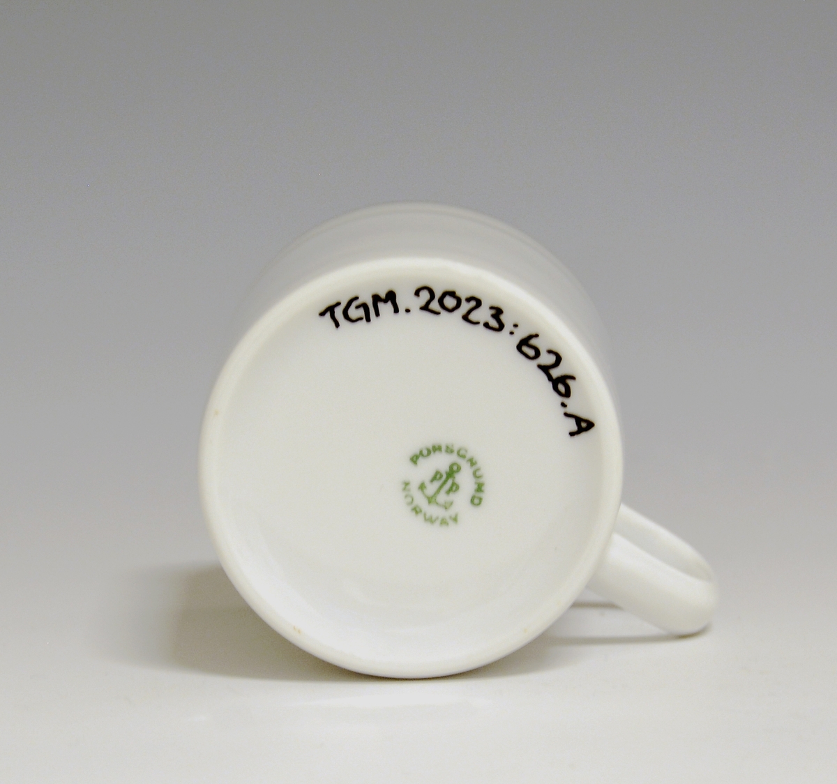 Kopp av porselen med hvit glasur. Dekorert med to enkle striper i platina med et grått bånd i mellom øverst på korpus.
Modell: Saturn
Dekor: Platina
