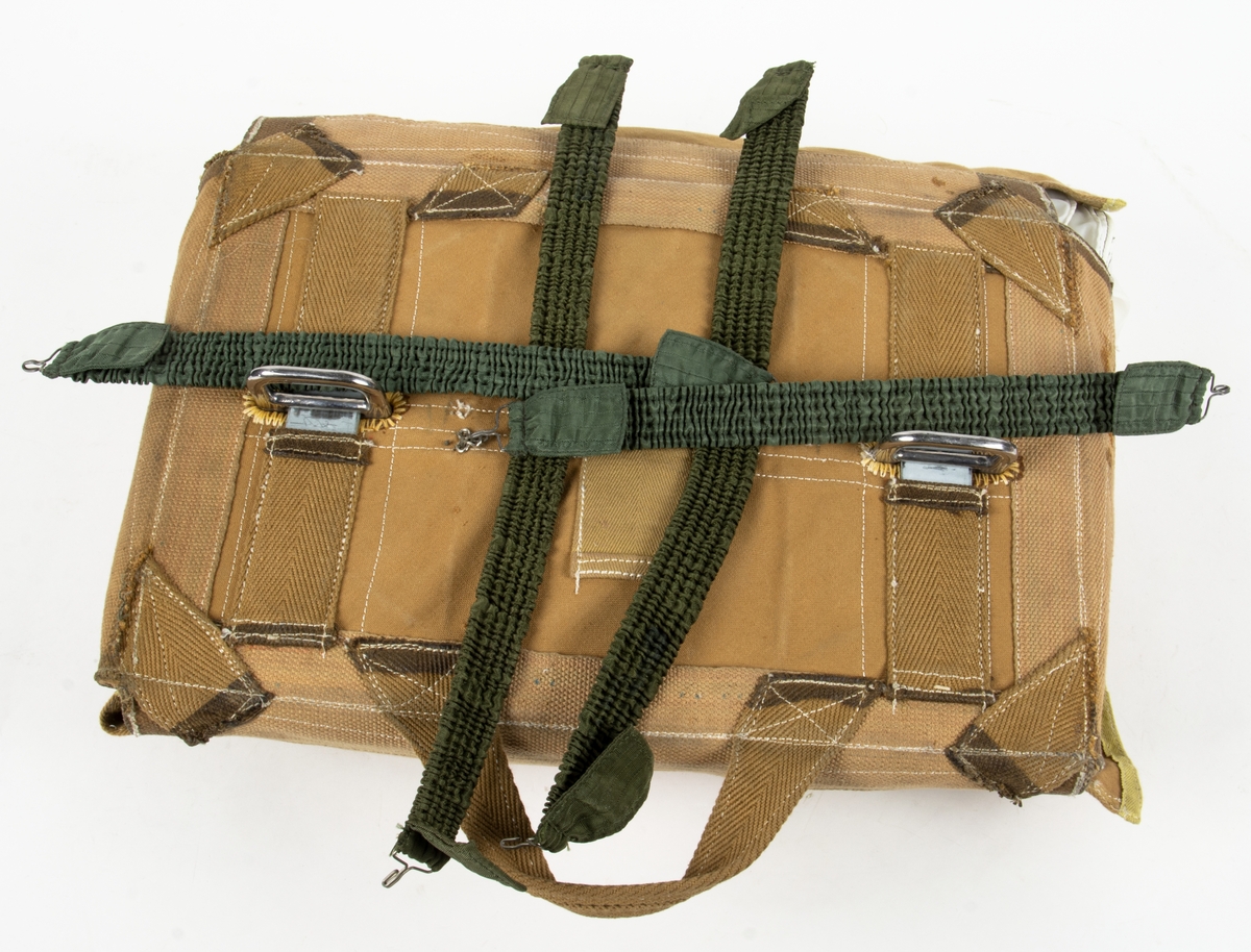 Bröstfallskärm, FASK 22. G.Q, Typ C. Mk.2.
Remmarnas utlösningsmekanism är helt mekanisk. Hölje av smärtingduk. Vit kalott av nylon. Skärmen är utlöst och stämplad Kasserad.
Medföljande tillhörande sele med remmar av sadelgjord.