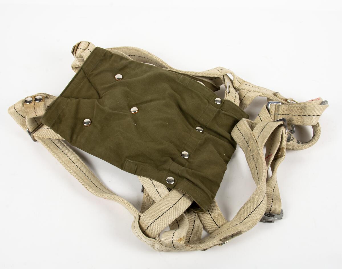 Bröstfallskärm, FASK 22. G.Q, Typ C. Mk.2.
Remmarnas utlösningsmekanism är helt mekanisk. Hölje av smärtingduk. Vit kalott av nylon. Skärmen är packad och stämplad Kasserad.
Medföljande sele med remmar av sadelgjord. Selen har individnumer 3834 och en etikett med texten; "Tillverkad av Irvin Fallskärmsaktiebolag Stockholm Sverige". (Osäkert om selen tillhör fallskärmen.)