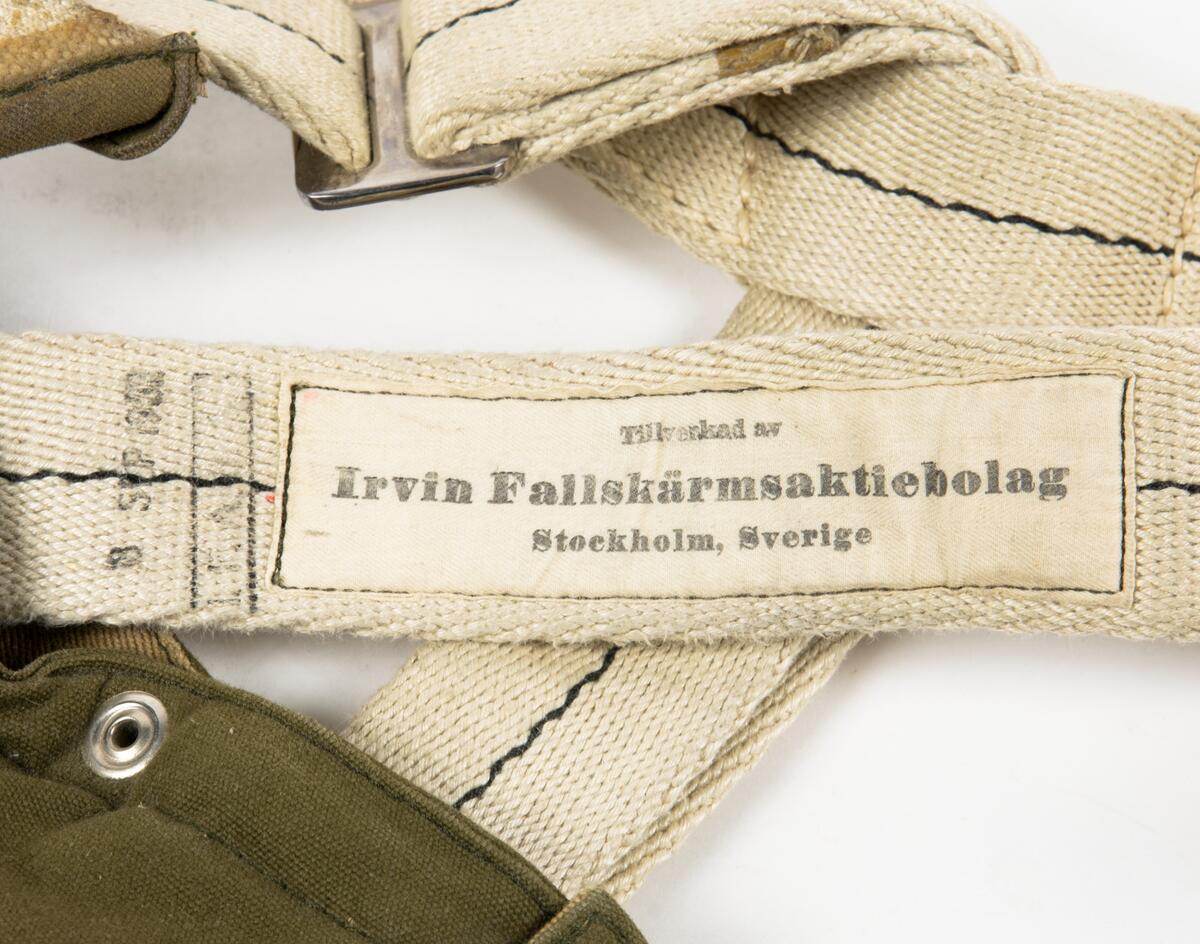 Bröstfallskärm, FASK 22. G.Q, Typ C. Mk.2.
Remmarnas utlösningsmekanism är helt mekanisk. Hölje av smärtingduk. Vit kalott av nylon. Skärmen är packad och stämplad Kasserad.
Medföljande sele med remmar av sadelgjord. Selen har individnumer 3834 och en etikett med texten; "Tillverkad av Irvin Fallskärmsaktiebolag Stockholm Sverige". (Osäkert om selen tillhör fallskärmen.)