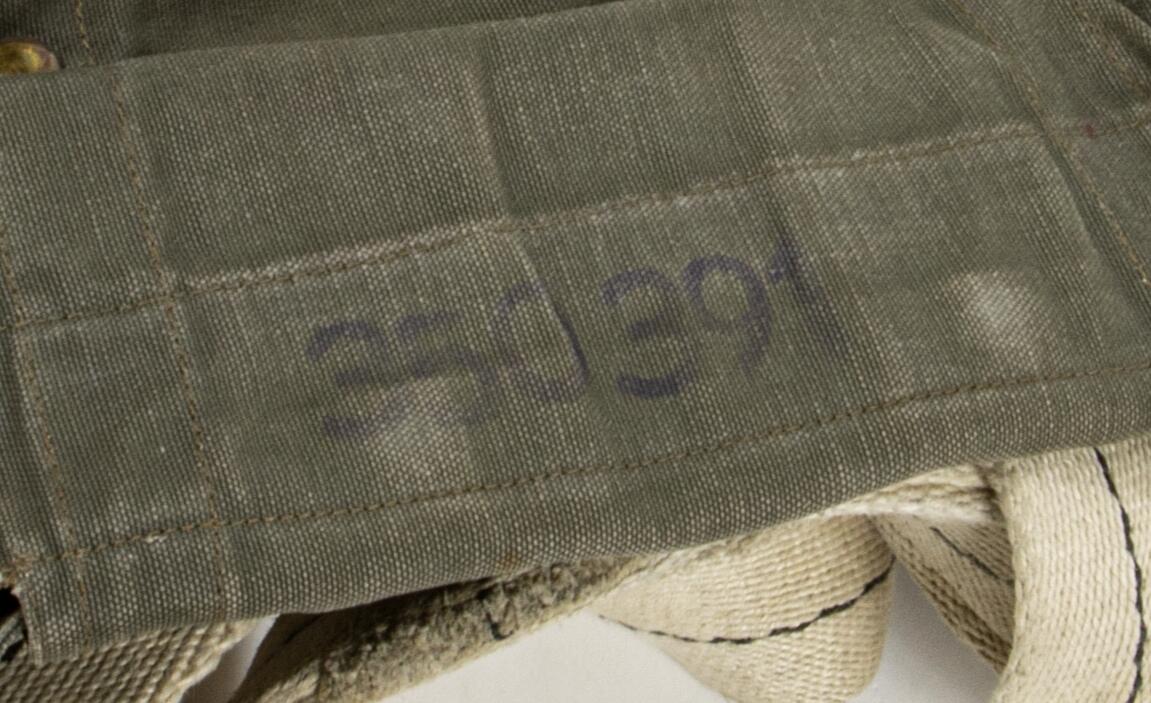 Bröstfallskärm, FASK 22. G.Q, Typ C. Mk.2.
Remmarnas utlösningsmekanism är helt mekanisk. Hölje av smärtingduk. Vit kalott av nylon. Skärmen är utlöst och stämplad Kasserad.
Medföljande tillhörande sele med remmar av sadelgjord.